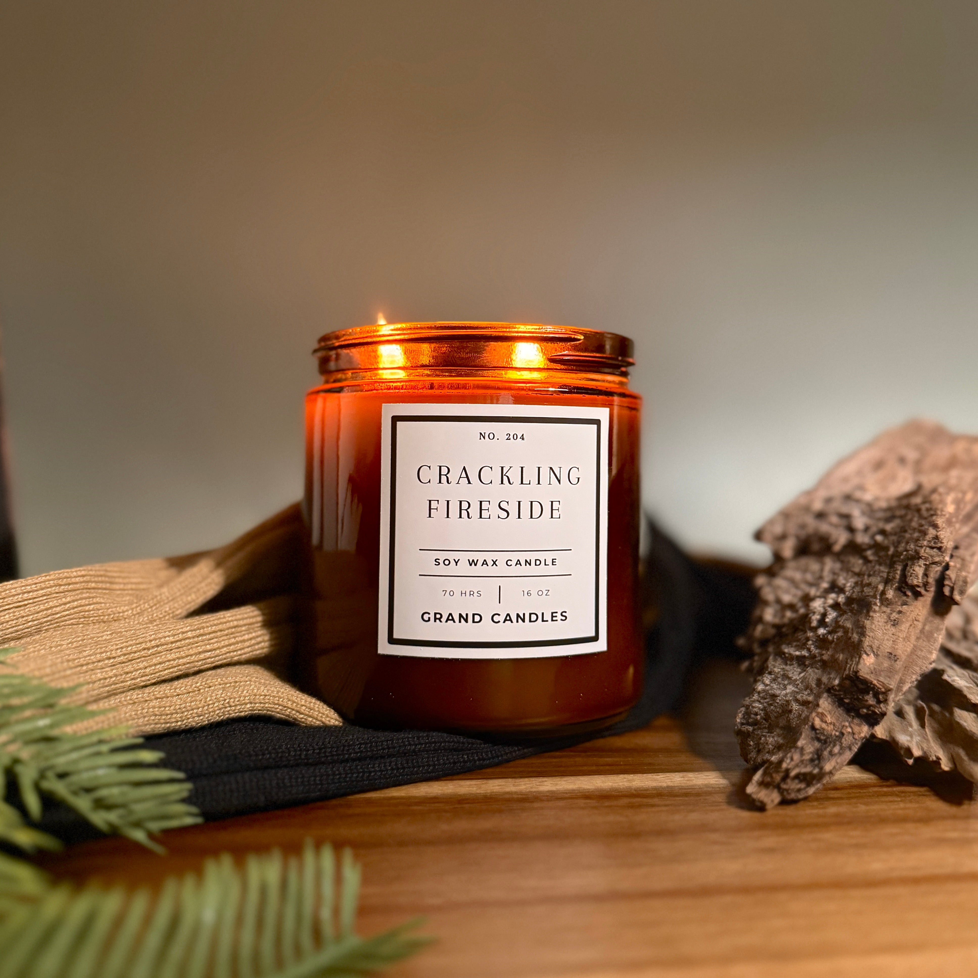 Candle labeled 'Crackling Fireside' by Grand Candles on a wooden surface with decorative elements.