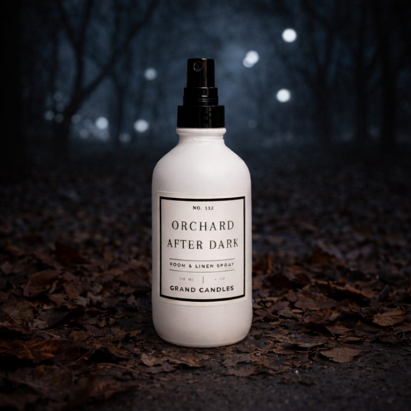 Orchard After Dark room spray by Grand Candles in a white 4 oz bottle photographed in a dark woodland setting
